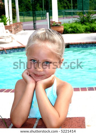 A cute child with long blonde hair and big baby blue eyes wearing a tropical print dress.