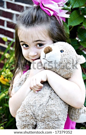 Beautiful young girl posing with her best friend, her Teddy Bear, in an outdoor setting.