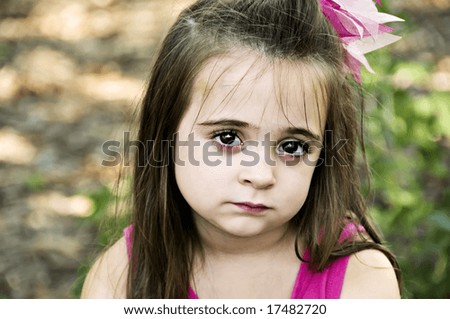 Beautiful brunette little girl posing with a sad facial expression.