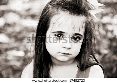 Beautiful brunette little girl posing with a sad facial expression in brown tones
