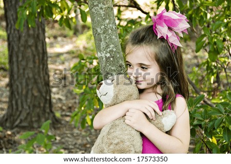Beautiful child  hugging her very best friend and playmate her stuffed bear.