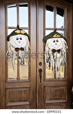 Two beautiful wooden doors dressed with scarecrow heads for fall.