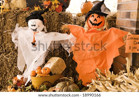 A fall display of ghosts, pumpkins, hay and fall leaves