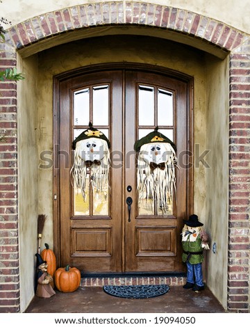 Double Doors decorated with scarecrow faces and other fall decorations.