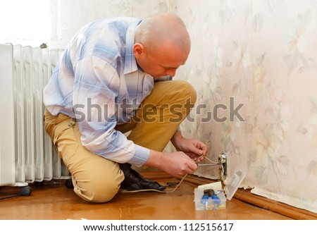 man repairing an electrical outlet while sitting on the floor