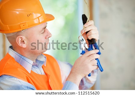 Electrician a helmet repairing ceiling wiring in the house