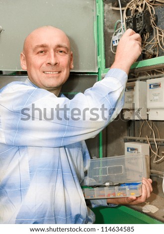 electrician man operating personnel installing and mounting new industrial wiring at voltage panel