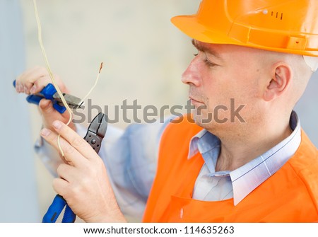 Electrician repairing ceiling wiring in the house