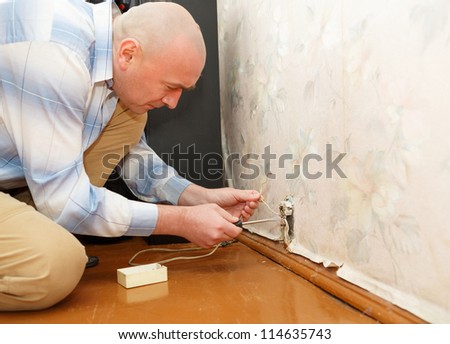 man fixing an electricity outlet within doors