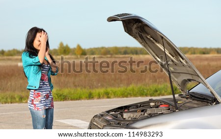 attractive brunette in front of her car broken down car