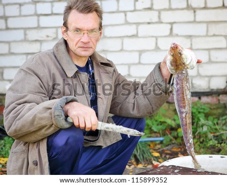 adult fisherman prepares fish in outdoors