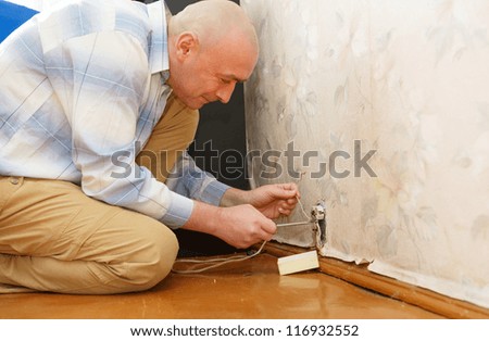 man fixing an electricity outlet within doors