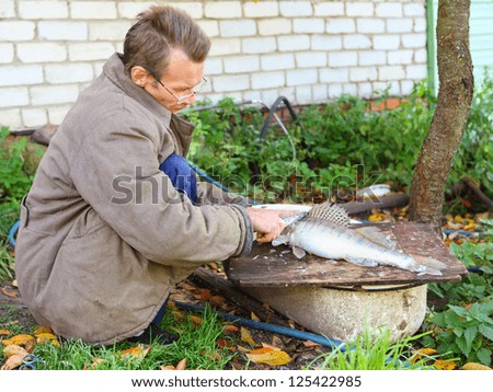 thin man cut up fish for cooking outdoors