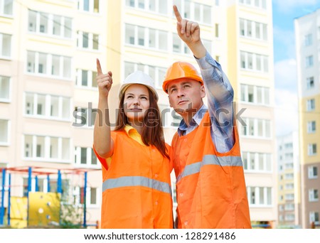 male and female construction workers in a helmet on a background of houses