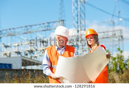 male and female construction workers in the helmet against electrical designs