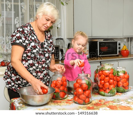 elderly woman and a child  preparing canned tomatoes
