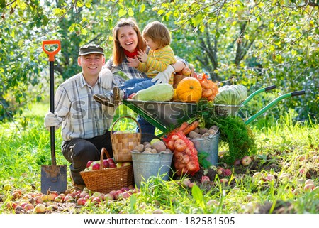 Happy family in the garden with a crop of vegetables and fruit