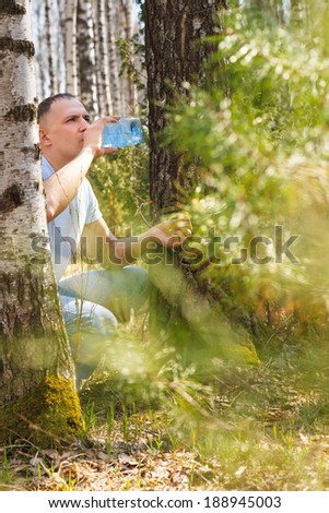 man drink birch sap in the spring forest