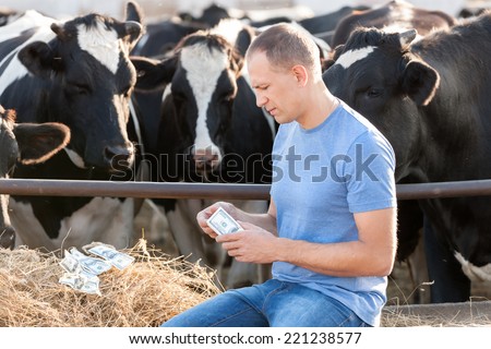 Men with money on a cow farm.Conceptual Image to Represent the Cost of  Raising  animals