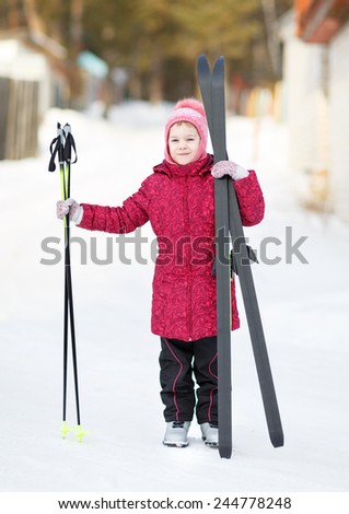 child standing in winter outfit with skis