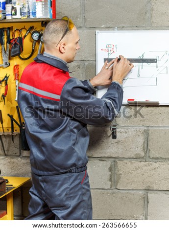 Construction worker  sketching blueprints on  drawing board