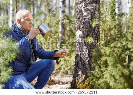 man in forest drinking from a cup tree sap