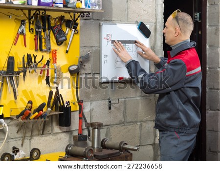 Mechanical technician writing on notepad in the factory