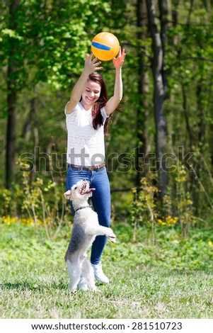 girl in motion Ball trains the dog in a summer park