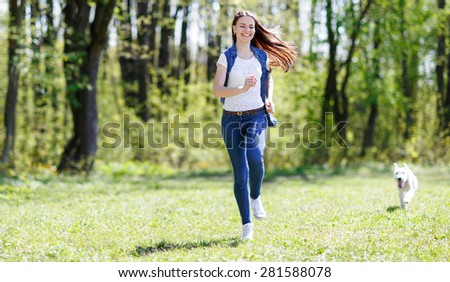 Happy athletic girl running with dog in the park