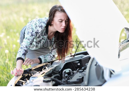 attractive brunette in front of her car broken down