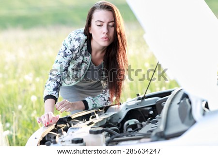 attractive brunette in front of her car broken down