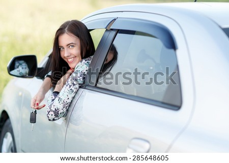 Girl looks out of  window holding car keys in hand