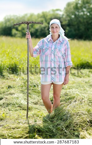 Woman farmer turns the hay with a hay fork