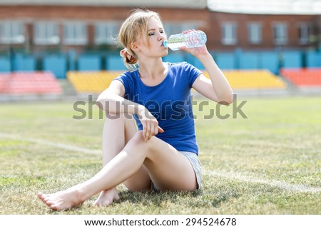 Portrait of healthy fitness girl drinking water. Woman drinking sports nutrition beverage while working out.