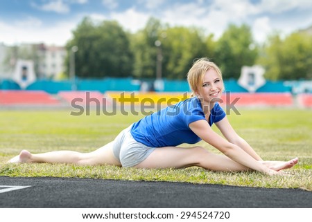 Young fit sporty woman stretching and heating up before training at a stadium .Fitness sport model training outside.