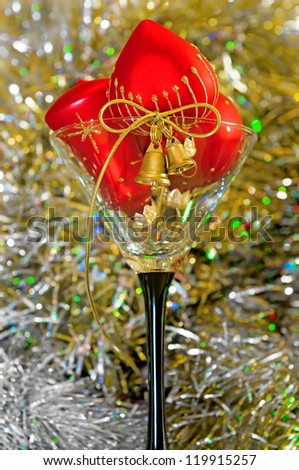 New Year\'s decorations, red heart balls and gold bells in glass on a bright color background