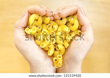 Pasta gomito in woman\'s  hands forming heart shape