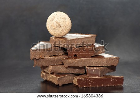 Chocolate stacked slices with a chocolate ball on the top on black background
