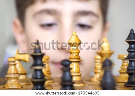 Chess game figures with a playing boy head on background