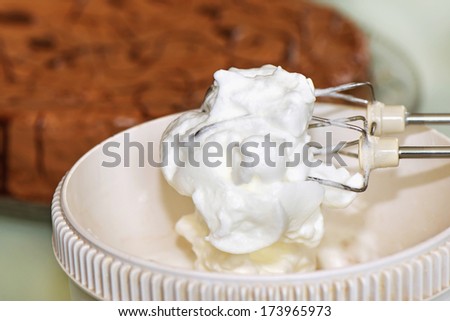 Raw meringue mousse in food processor with a cake in background