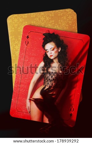 Queen of Spades. Young woman with art makeup and hair-do on background of playing cards on the table. Partly hidden by raven\'s shadow. Photo compilation. Textures.