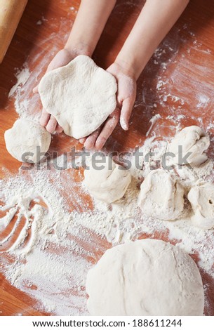 Child holding kneading dough on table. Kid\'s hands and fresh dough and flour. Cooking pies at home or  learning at culinary class.