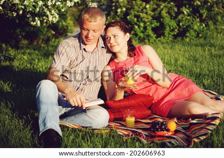 Young Couple in Love Outdoors, man reads book to his woman