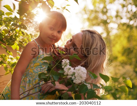 Happy family outdoors in summer forest, mother and kid, child, daughter smiling hugging