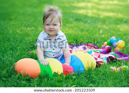 Smiling baby boy on background of toys and grass in park