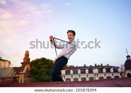 Young bold girl woman hipster on roof showing off tongue and stretching suspenders