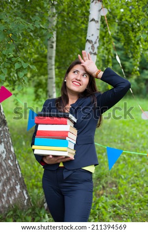 Beautiful happy asian woman girl teacher student in black suit holding heavy book pack with her hand above head outdoors