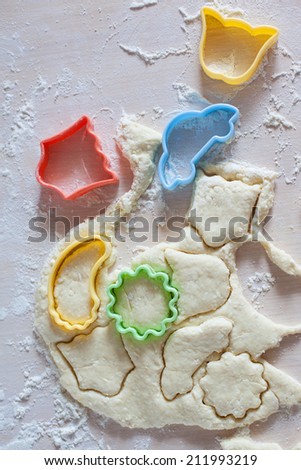 Thin dough on table with colorful plastic cake molds, raw cookies