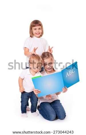 Group of happy kids sisters and brother reading book, isolated on white