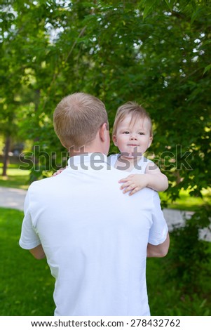Father dad parent holding baby boy outdoors in summer garden